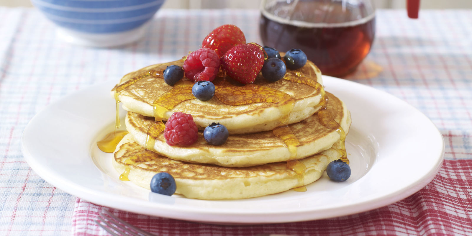 Stacked pancakes with berries and maple syrup on a plate